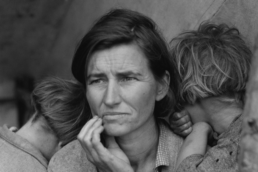 Fotografía de 1936: una madre migrante con sus hijas apoyadas en sus hombros, mirando a lo lejos